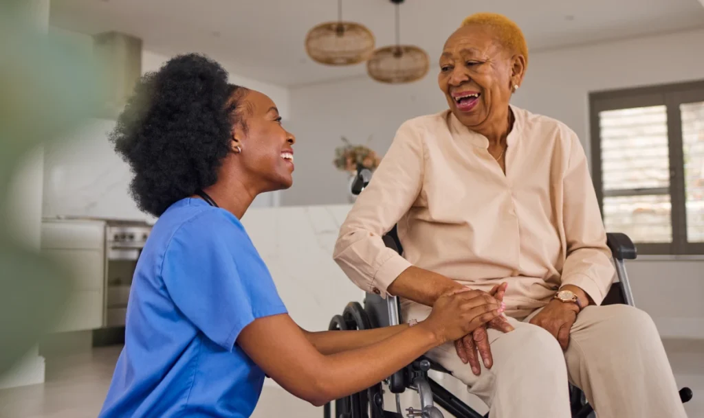 Caregiver smiling with elderly wheelchair patient.