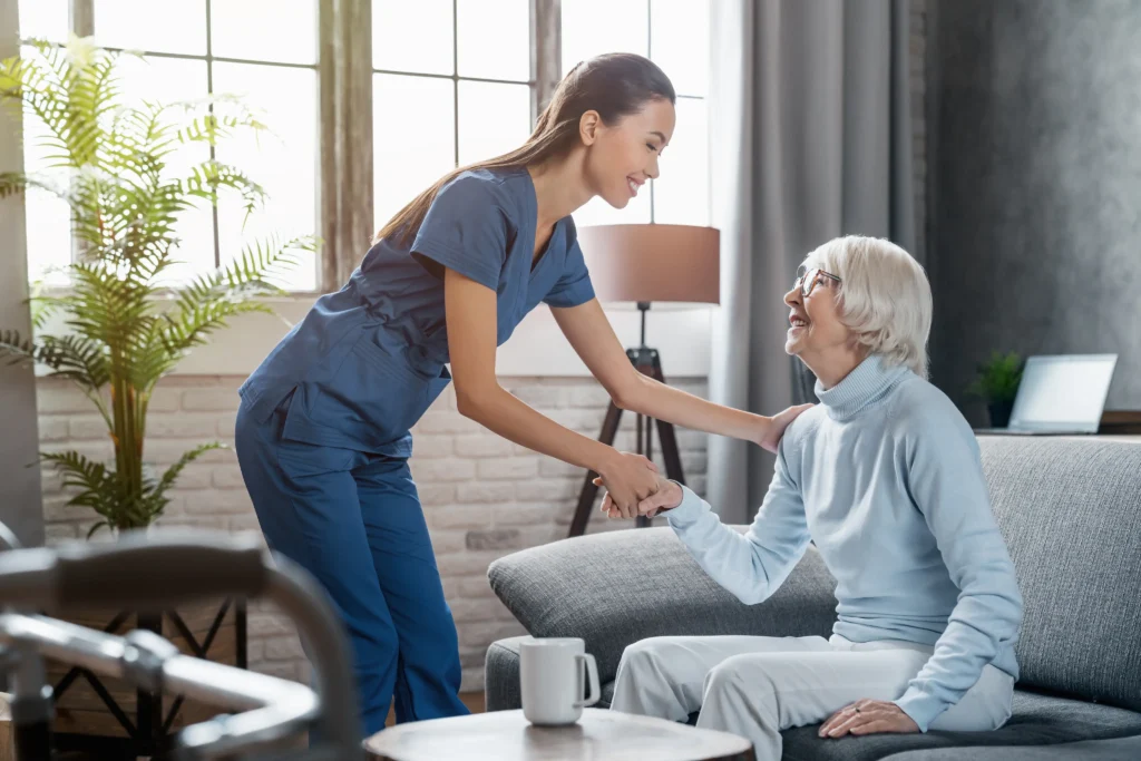 Caregiver helping elderly woman stand up.
