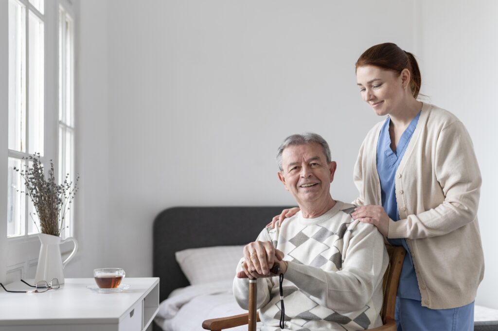 Caregiver supporting smiling elderly man indoors.