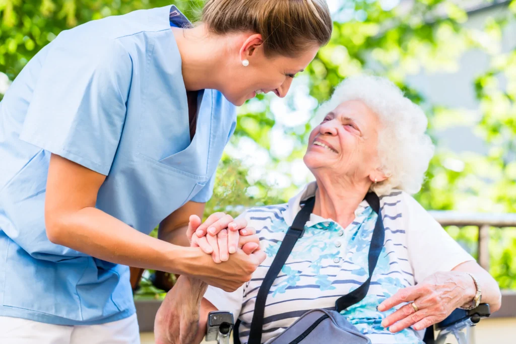 Caregiver holding hands with smiling elderly woman.