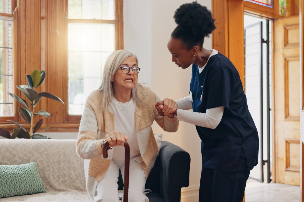 Caregiver assisting elderly woman standing up.