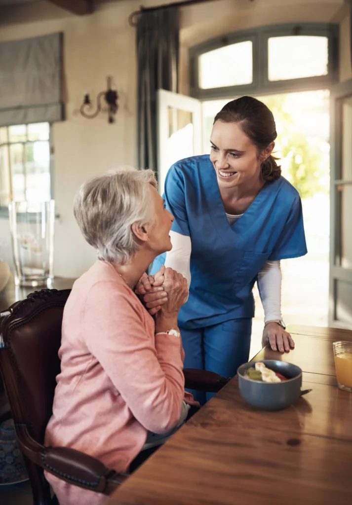 Caregiver supporting elderly woman during meal.