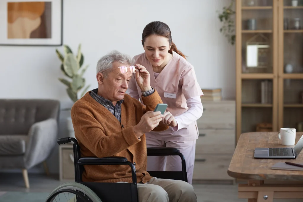 Caregiver assisting elderly man with smartphone.