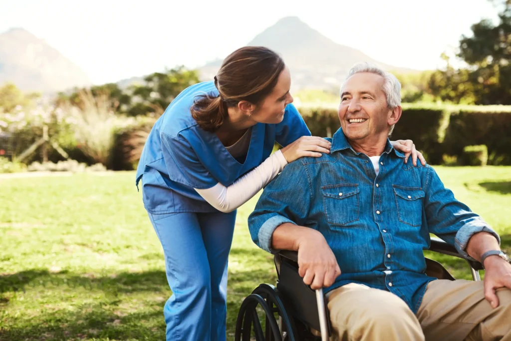 Caregiver comforting smiling elderly man outdoors.