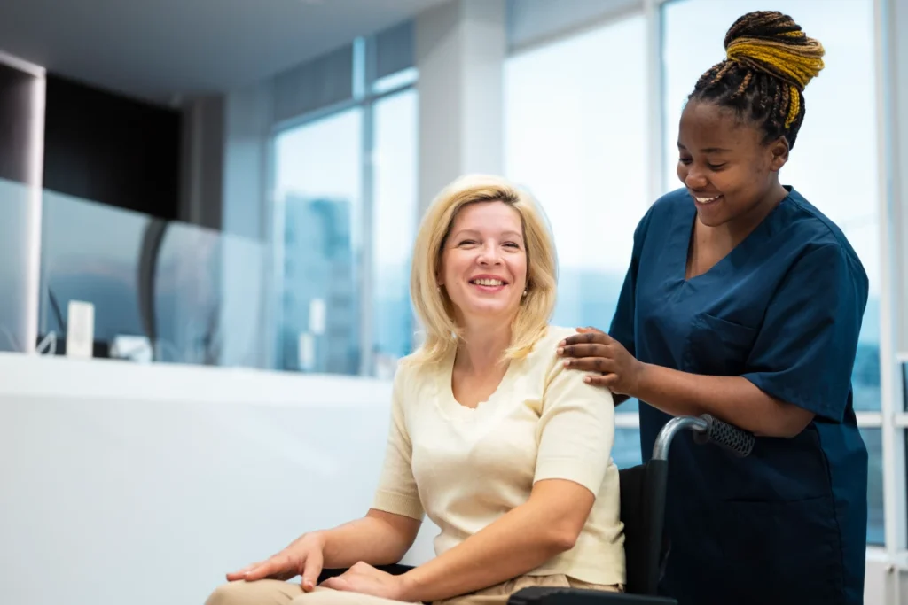 Nurse supporting smiling woman in wheelchair.