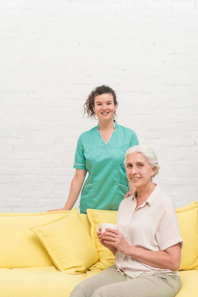 Caregiver standing beside smiling elderly woman.