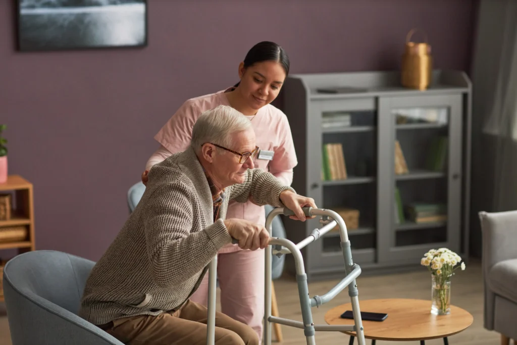 Caregiver assisting elderly man using walker.