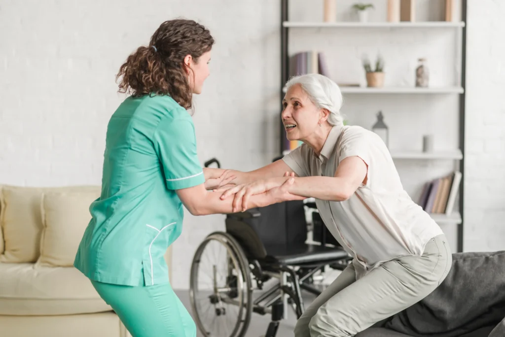 Caregiver assisting an elderly woman as she stands up.