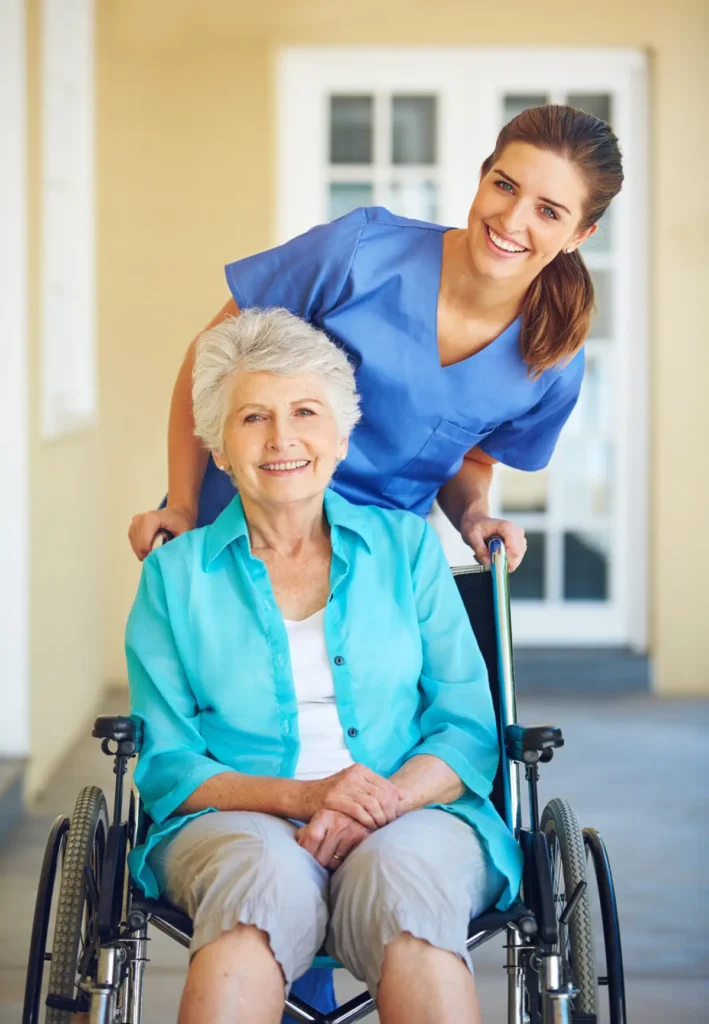 Smiling caregiver with elderly woman in wheelchair.