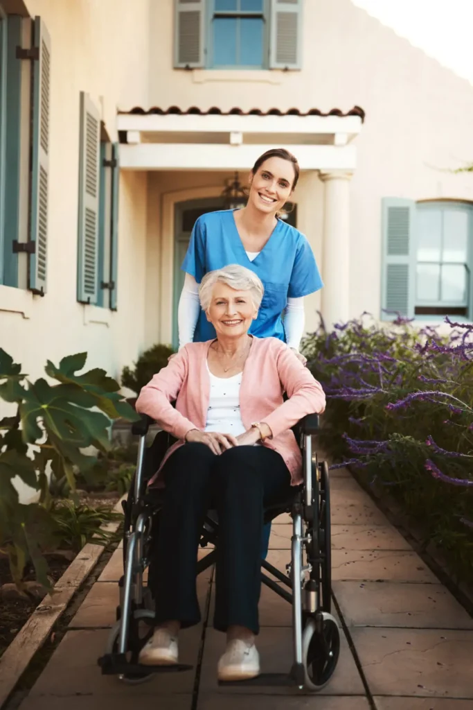 Caregiver pushing smiling elderly woman outdoors.
