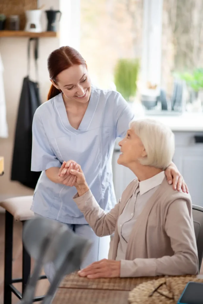 Caregiver comforting elderly woman at table.
